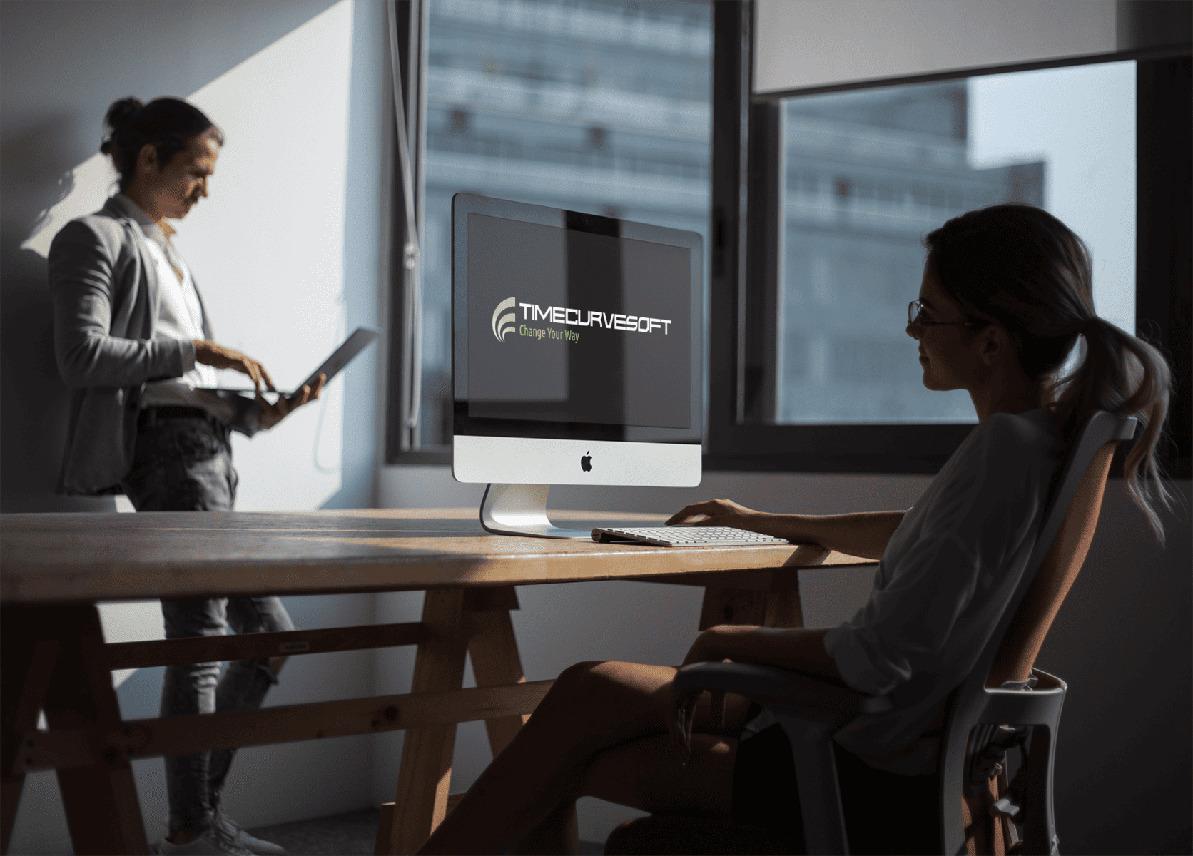 girl working with an imac mockup near the window with her coworker a20977
